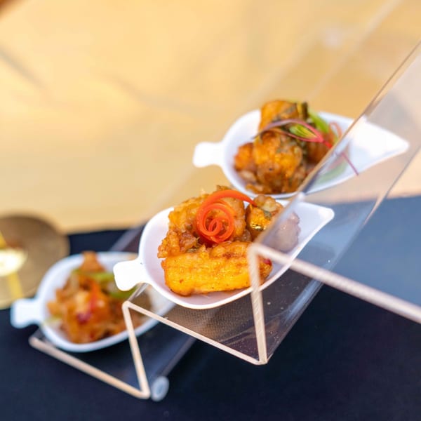 Three Indian appetizers, including fried paneer with red chili garnish, displayed on a tiered stand.