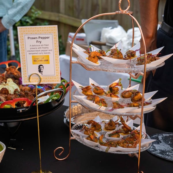 A three-tiered stand displays individual servings of Prawn Pepper Fry from The Yellow Chilli.