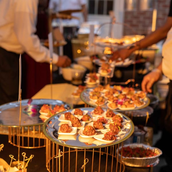 Indian appetizers, possibly from The Yellow Chilli, on tiered serving trays at a buffet.